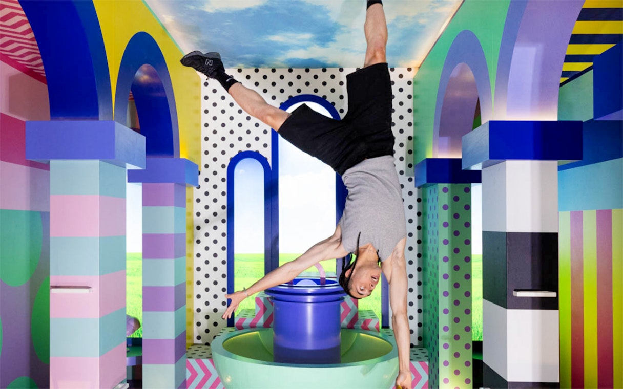 Person doing a handstand in colorful, upside-down room at The Upside Down Berlin.