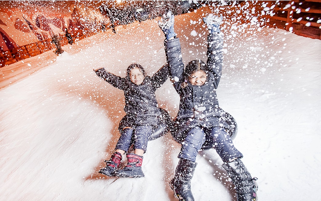Guests sliding down snowy slope at Singapore Snow City.