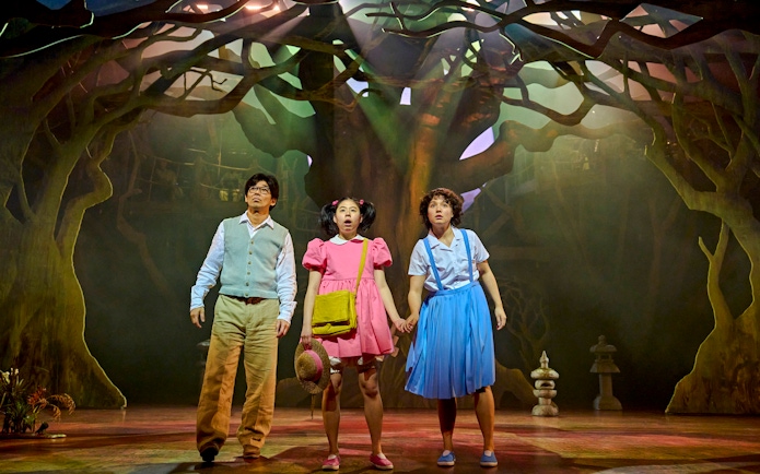 Stage scene from My Neighbour Totoro with three actors in a forest setting.