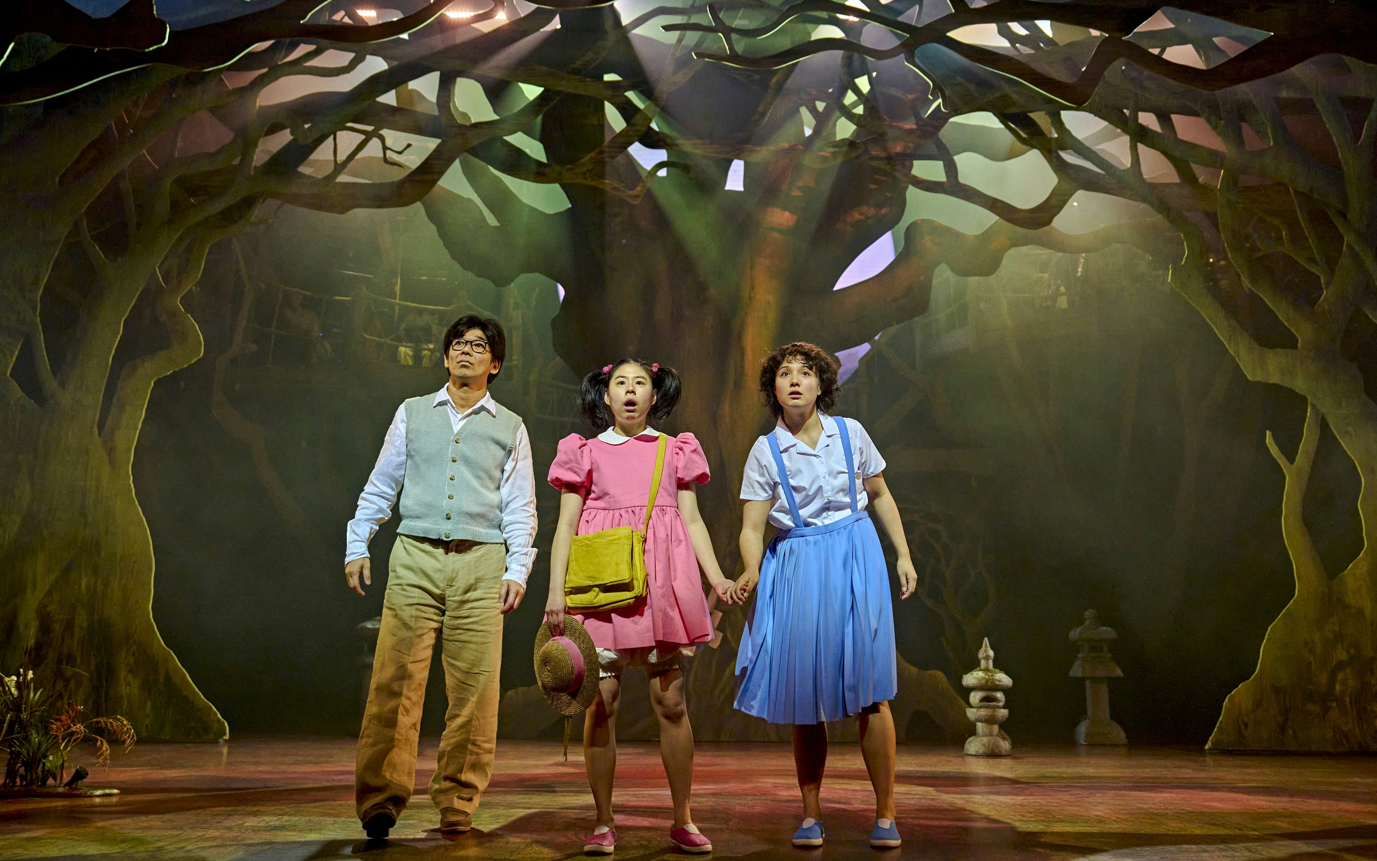 Stage scene from My Neighbour Totoro with three actors in a forest setting.