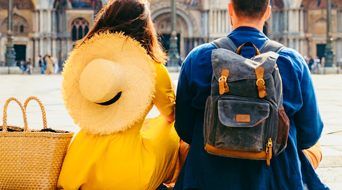 Couple sitting in St. Mark's Square, Venice, with Basilica di San Marco in the background.