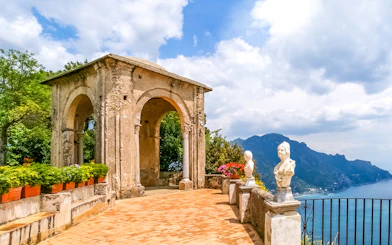 Terrace with statues and archway at Villa Cimbrone, overlooking Amalfi Coast.
