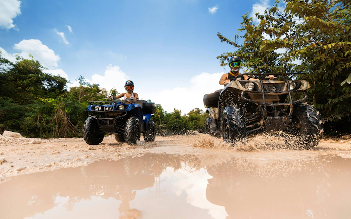 ATVs splashing through mud at Cancun Extreme Adventuring Park.