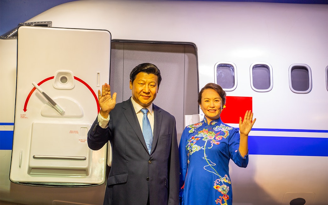 Wax figures of two people waving in front of an airplane at Madame Tussauds Bangkok.