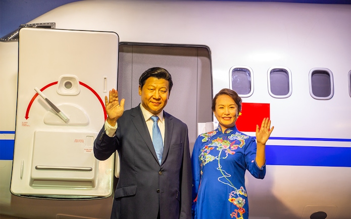 Wax figures of two people waving in front of an airplane at Madame Tussauds Bangkok.