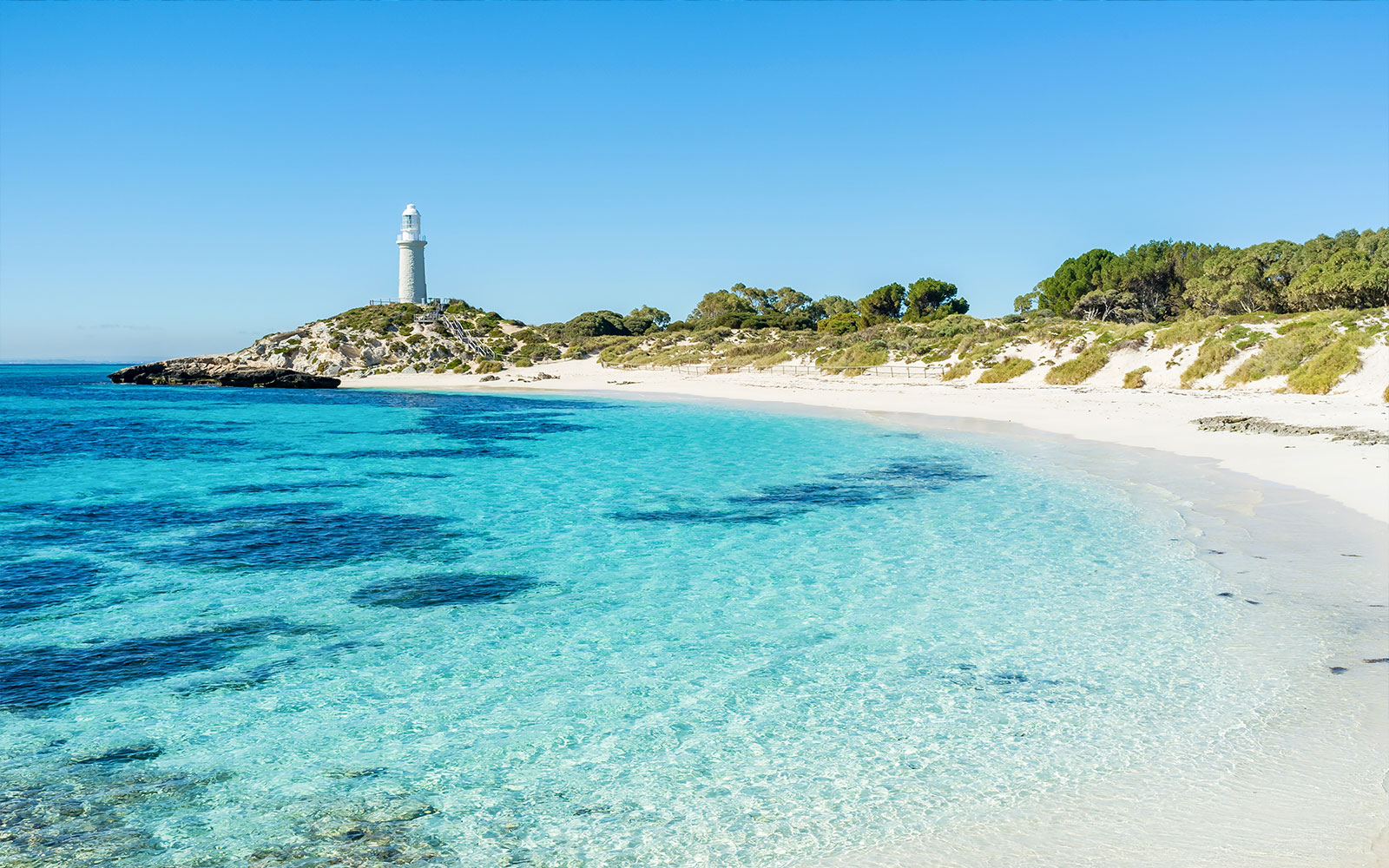 Rottnest Island lighthouse overlooking clear turquoise waters and sandy beach, Australia.