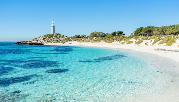 Rottnest Island lighthouse overlooking clear turquoise waters and sandy beach, Australia.