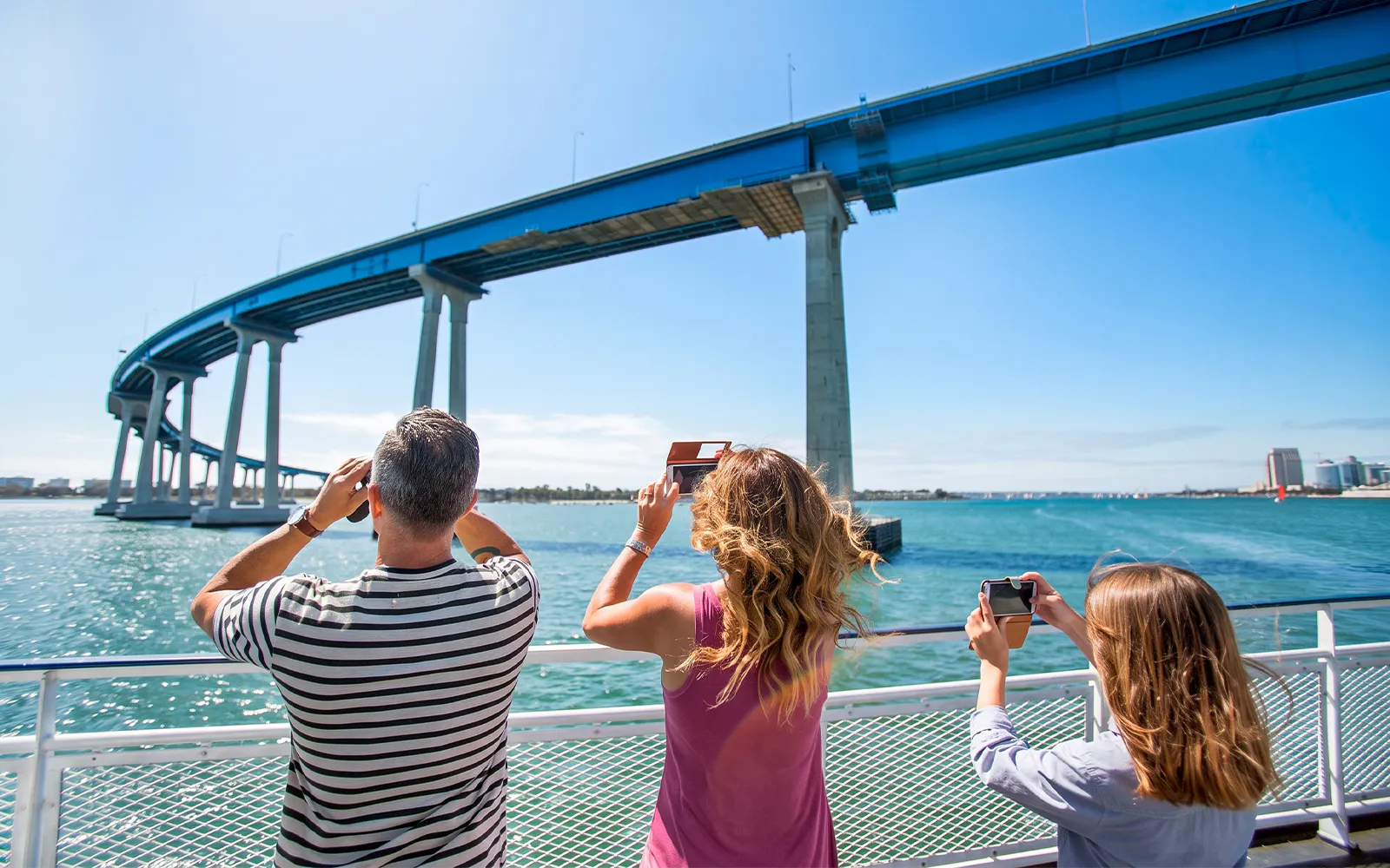 Guests on a San Diego cruise looking for whales and dolphins near a bridge.