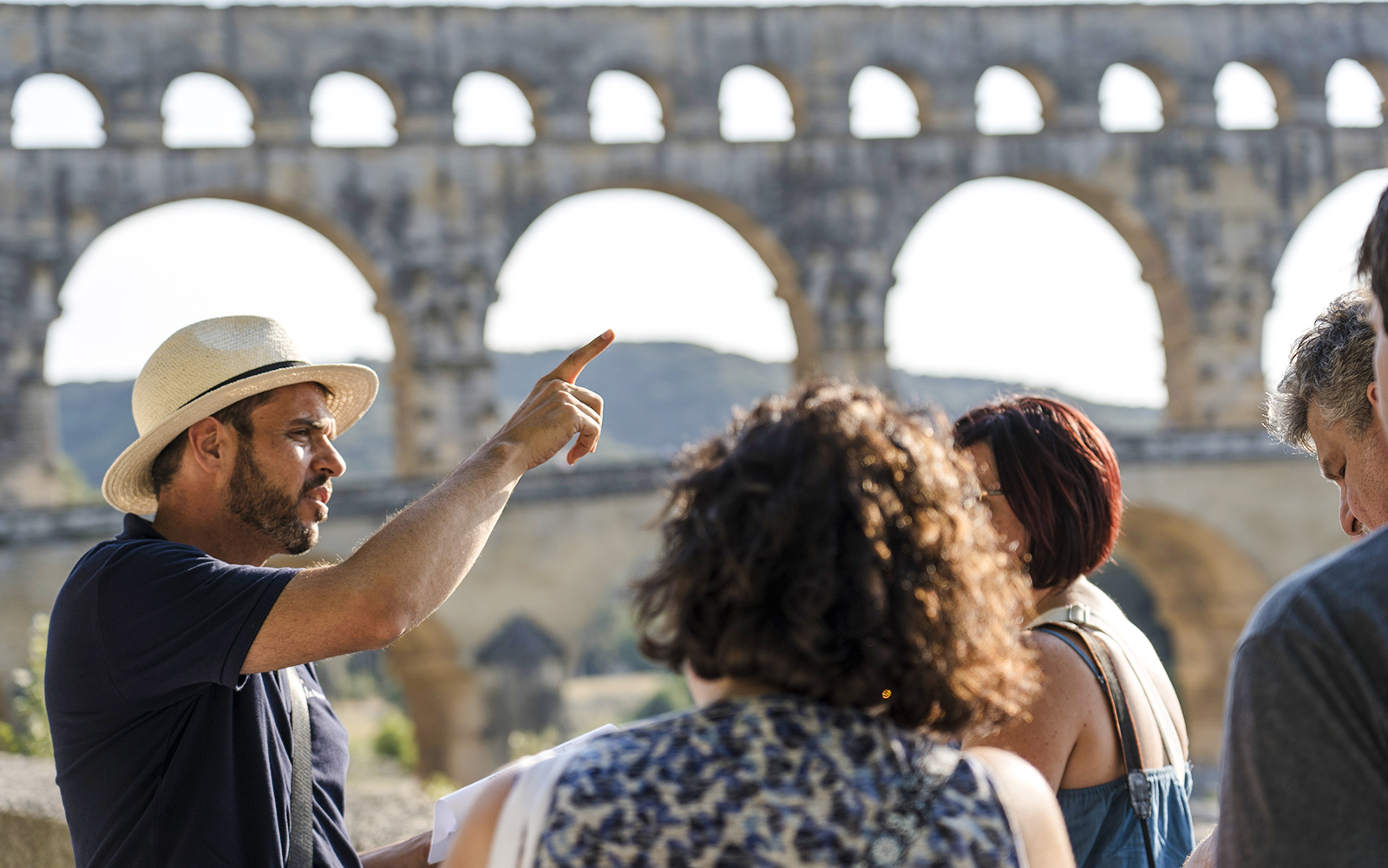Tour guide explaining Pont du Gard to a group of visitors in France.