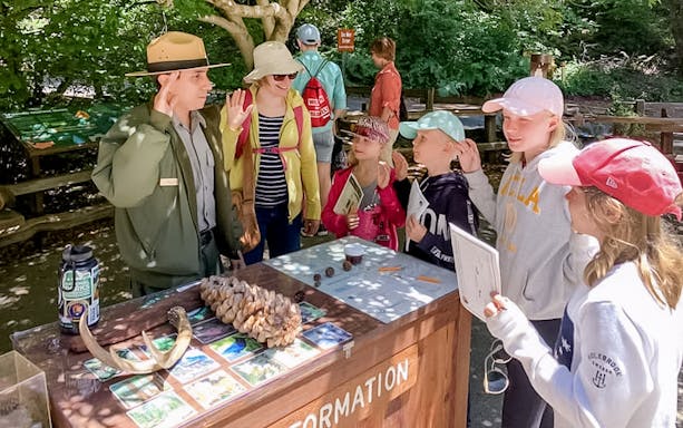 Park ranger engaging with children at an information booth in Muir Woods.