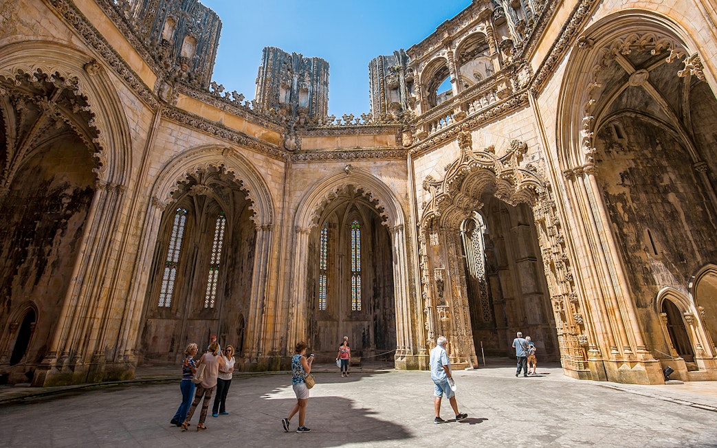 Visitors exploring the ornate architecture inside Batalha Monastery, Portugal.