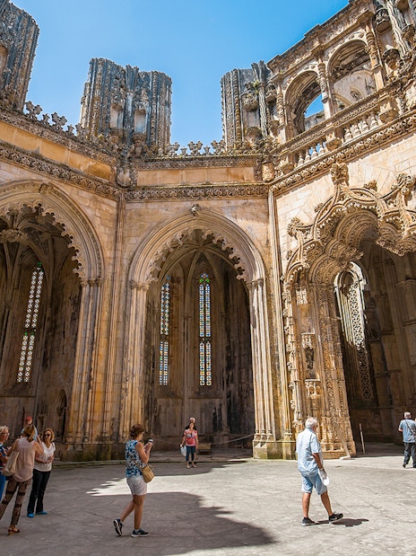 Visitors exploring the ornate architecture inside Batalha Monastery, Portugal.