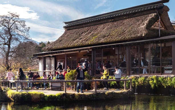 Visitors at a traditional thatched-roof house near Mount Fuji, Japan.