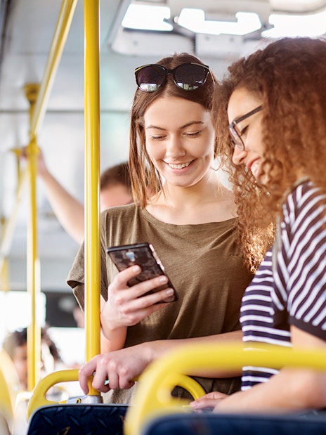 Two women on a bus checking phone, Fiumicino Airport to Naples transfer.