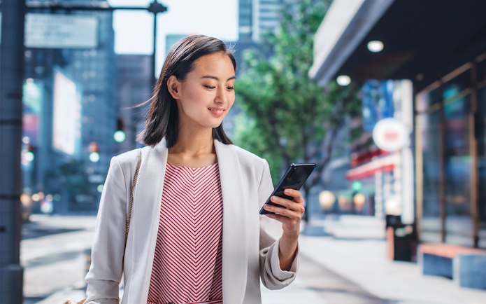 Person using smartphone on a city street in Japan.