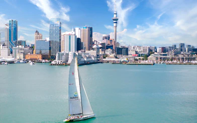 Sailboat on Waitemata Harbour with Auckland skyline in the background during America's Cup experience.