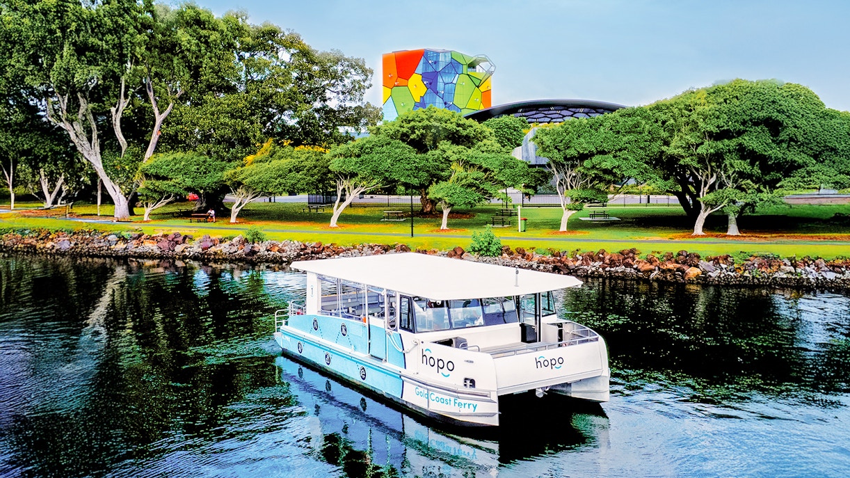 Traghetto della Gold Coast vicino alla Home of the Arts con edifici colorati e alberi rigogliosi sullo sfondo.