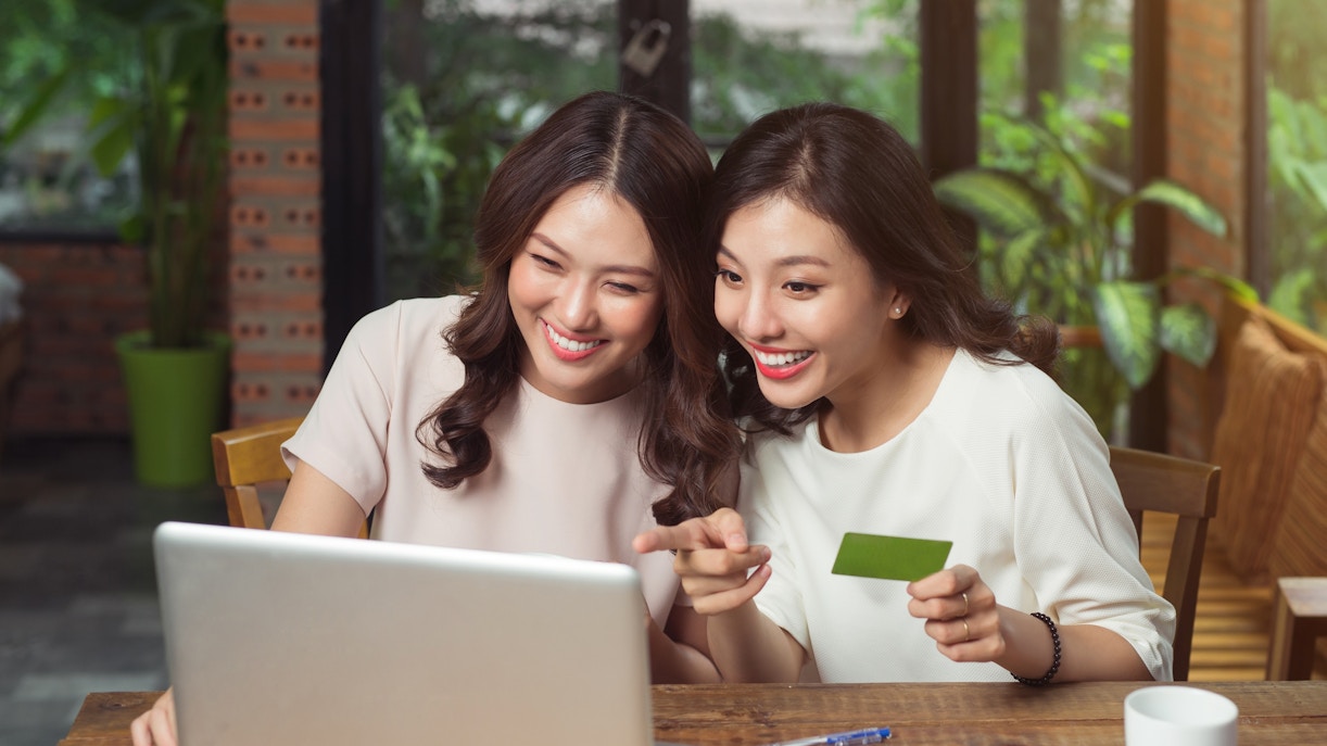 Two women using a laptop for online shopping.