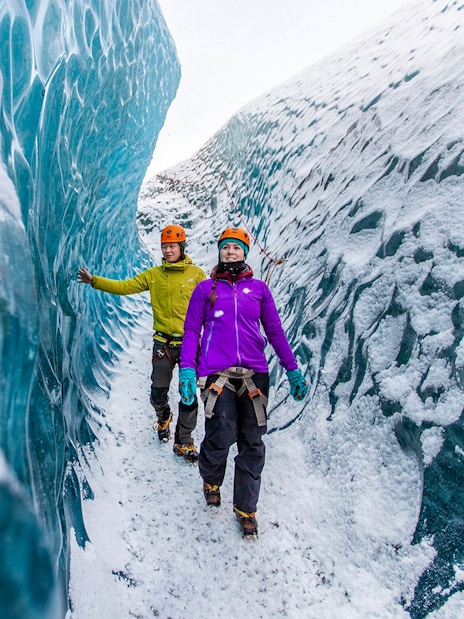 Hikers exploring icy crevasse on Falljökull glacier.