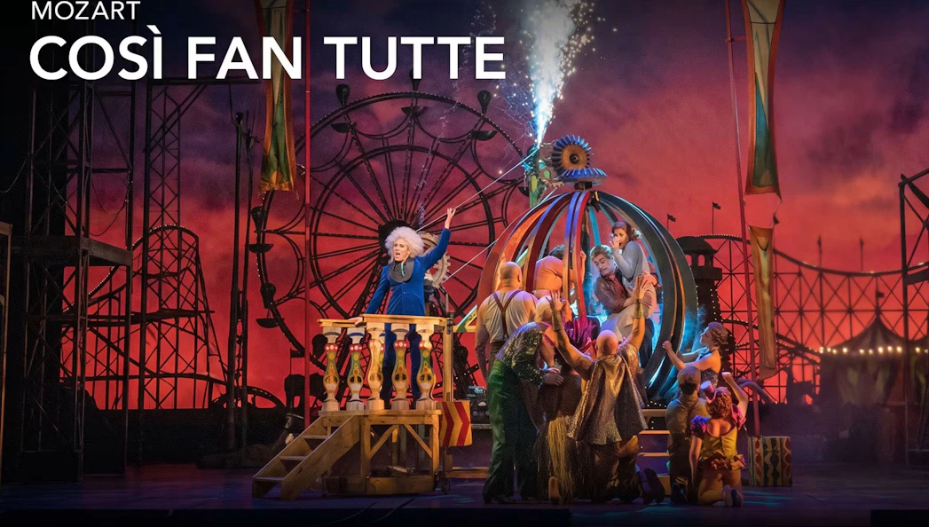Stage performance of "Cosi fan tutte" on Broadway with vibrant carnival backdrop.