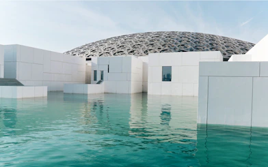 Louvre Museum Abu Dhabi exterior with dome and reflecting water.