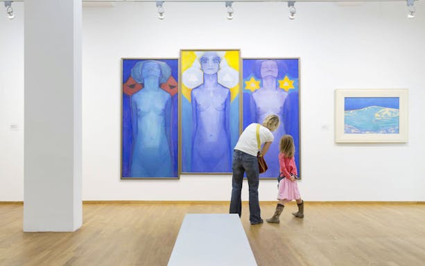 Visitors viewing modern art paintings in a gallery.