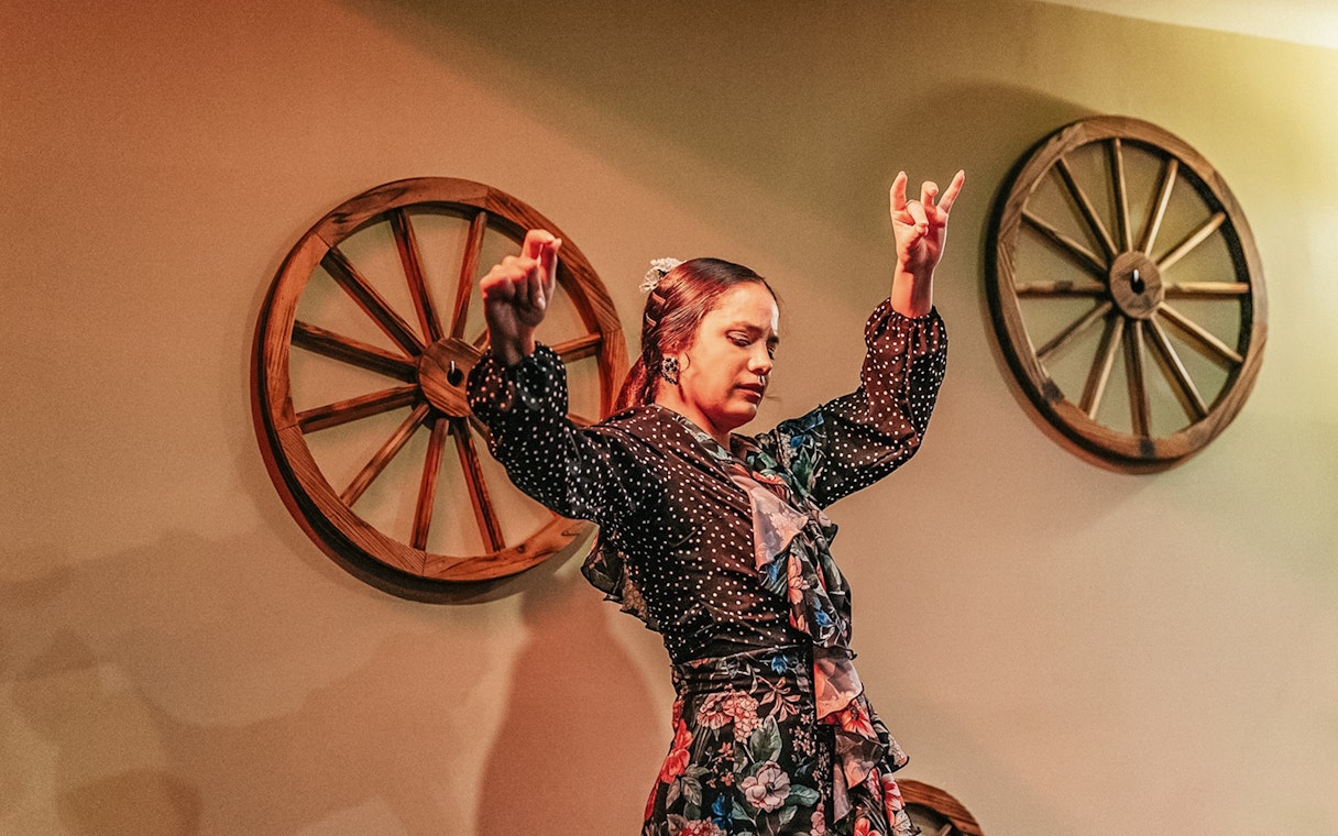 Flamenco dancer performing at a show with wooden wheel decor.