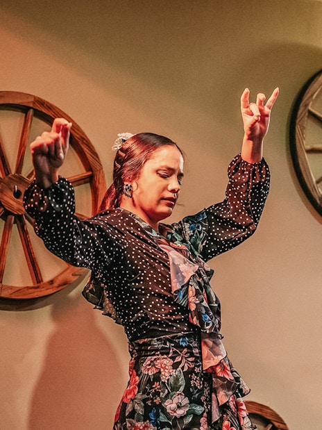 Flamenco dancer performing at a show with wooden wheel decor.