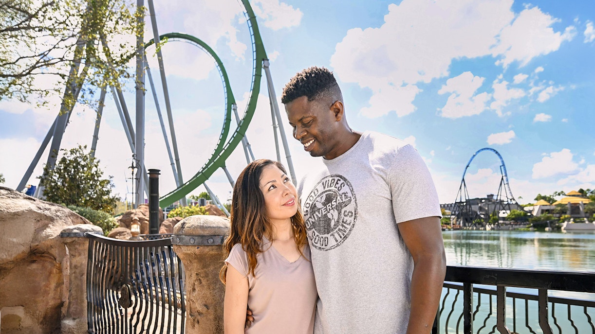Couple posing with rollercoaster in background at Universal Studios Orlando.