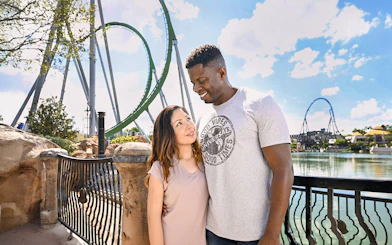 Couple posing with rollercoaster in background at Universal Studios Orlando.