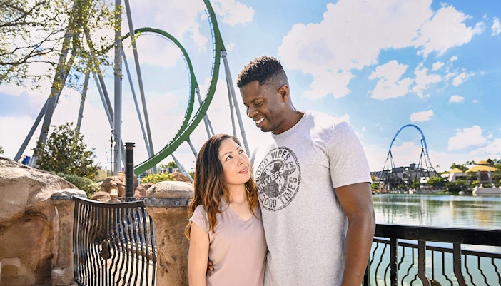 Couple posing with rollercoaster in background at Universal Studios Orlando.