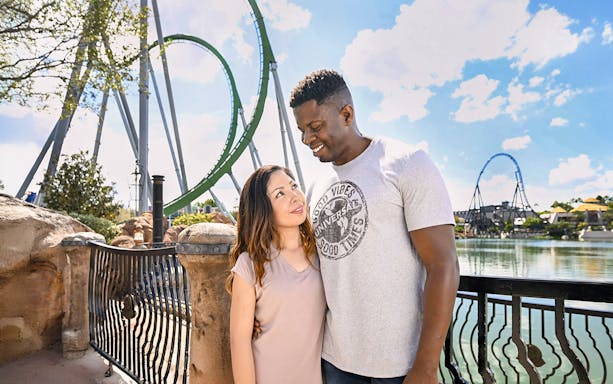 Couple posing with rollercoaster backdrop at Universal Studios Resort, Orlando.