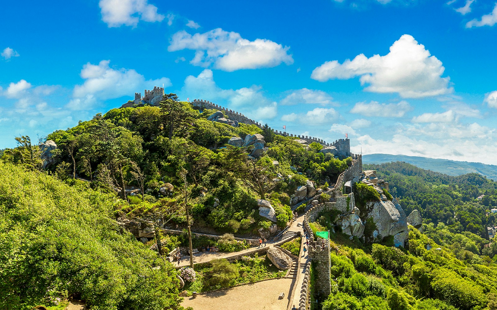 Moorish Castle in Lisbon with stone walls and lush greenery on a hilltop.