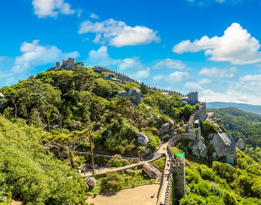 Moorish Castle in Lisbon with stone walls and lush greenery on a hilltop.