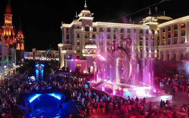 Crowd enjoying the illuminated gate show at Land of Legends, Antalya, Turkey at night.