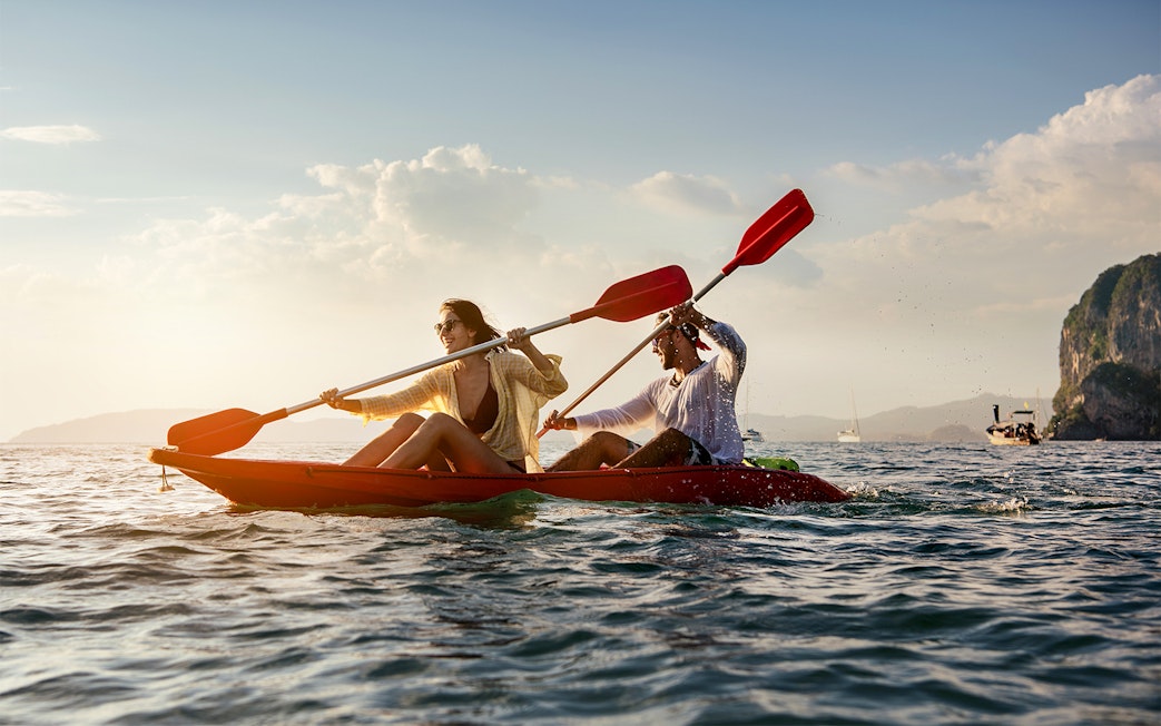 Two people kayaking on the ocean near cliffs, San Diego All-Inclusive Pass.