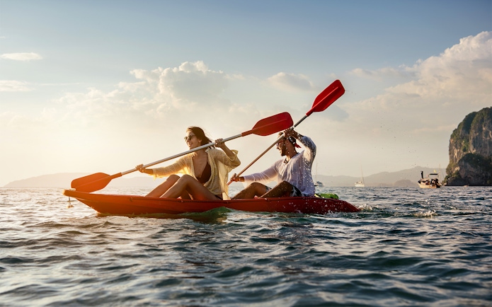 Two people kayaking on the ocean near cliffs, San Diego All-Inclusive Pass.