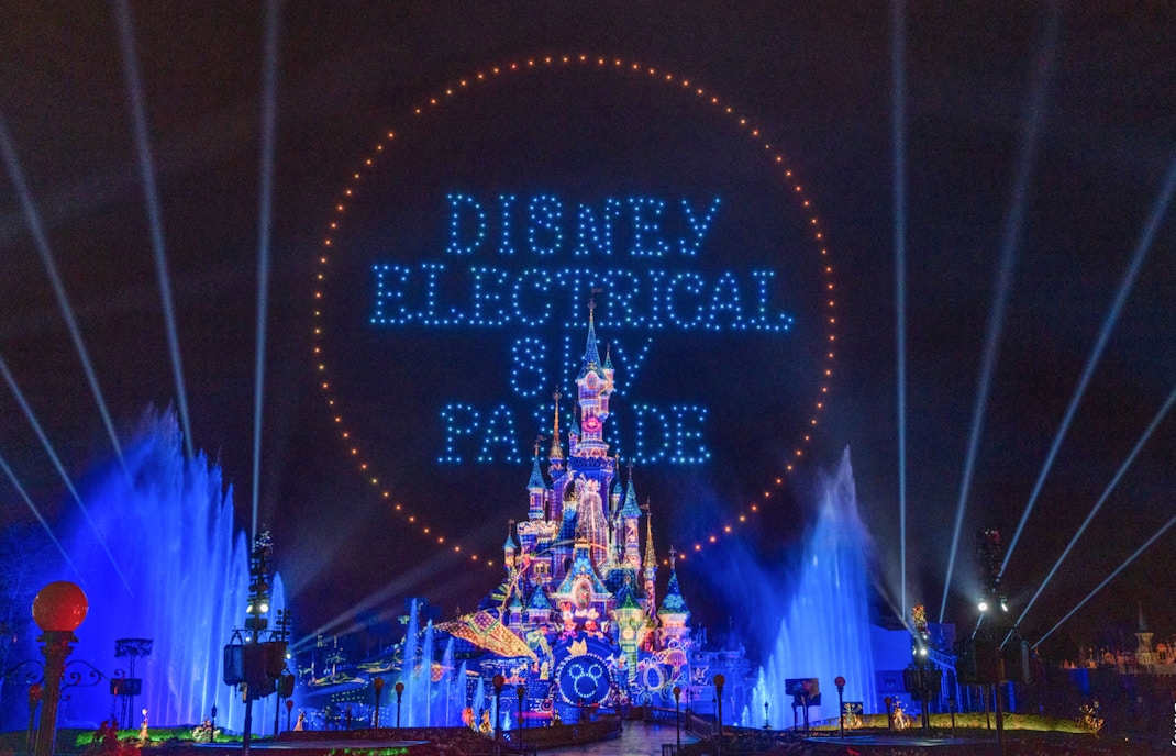 Disneyland Paris Electrical Parade with illuminated floats and characters at night.