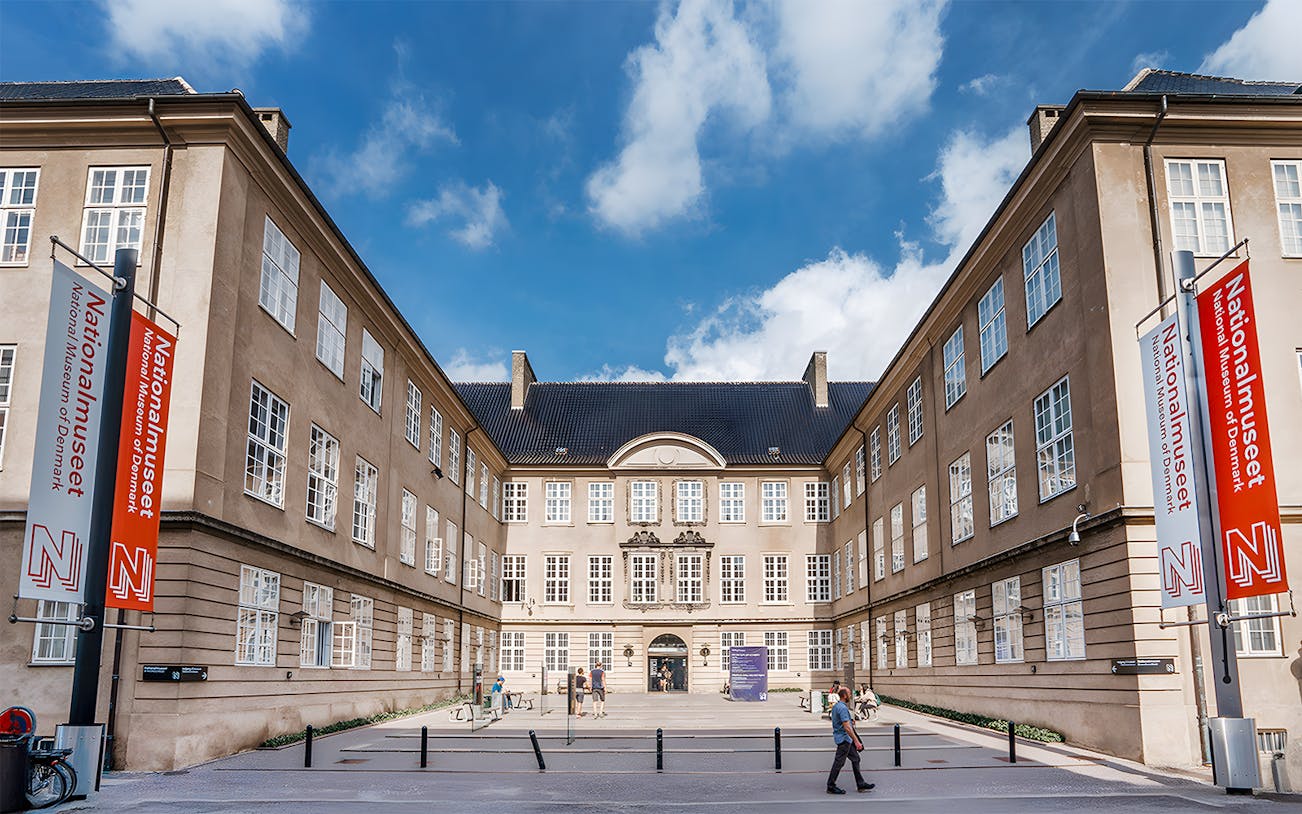 Exterior view of the National Museum of Denmark with entrance and banners.