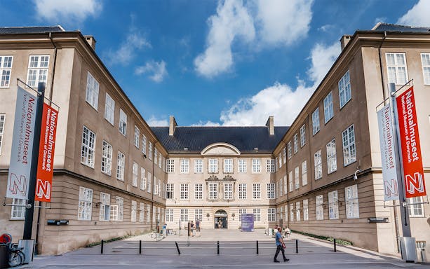 Exterior view of the National Museum of Denmark with entrance and banners.