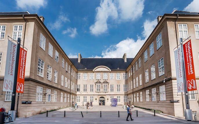 Exterior view of the National Museum of Denmark with entrance and banners.