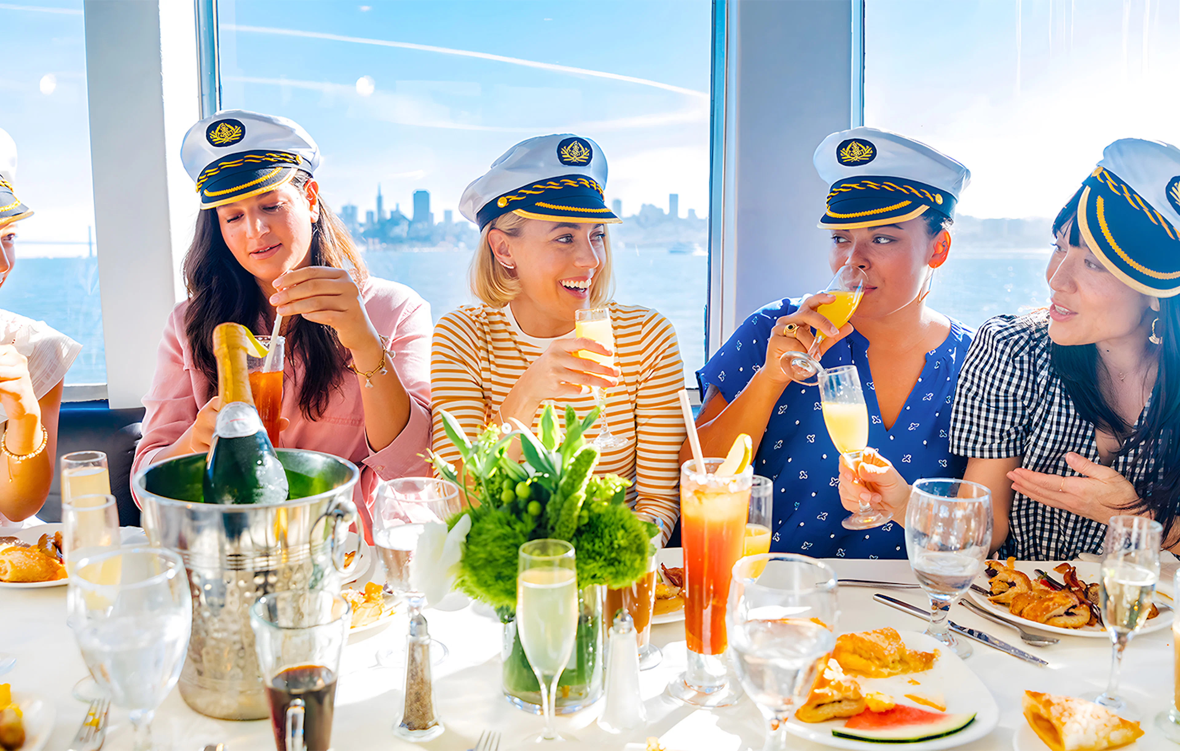 Guests enjoying drinks and dining on a New York Signature Dinner Cruise with city skyline views.