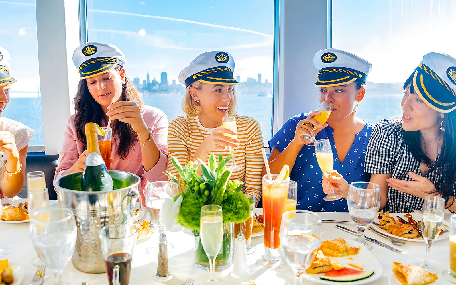 Guests enjoying drinks and dining on a New York Signature Dinner Cruise with city skyline views.