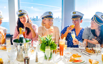 Guests enjoying drinks and dining on a New York Signature Dinner Cruise with city skyline views.