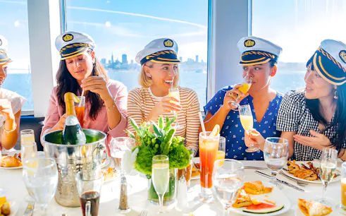 Guests enjoying drinks and dining on a New York Signature Dinner Cruise with city skyline views.