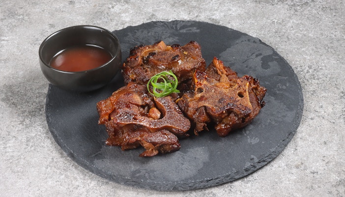 Oxtail dish with sauce on a slate plate.