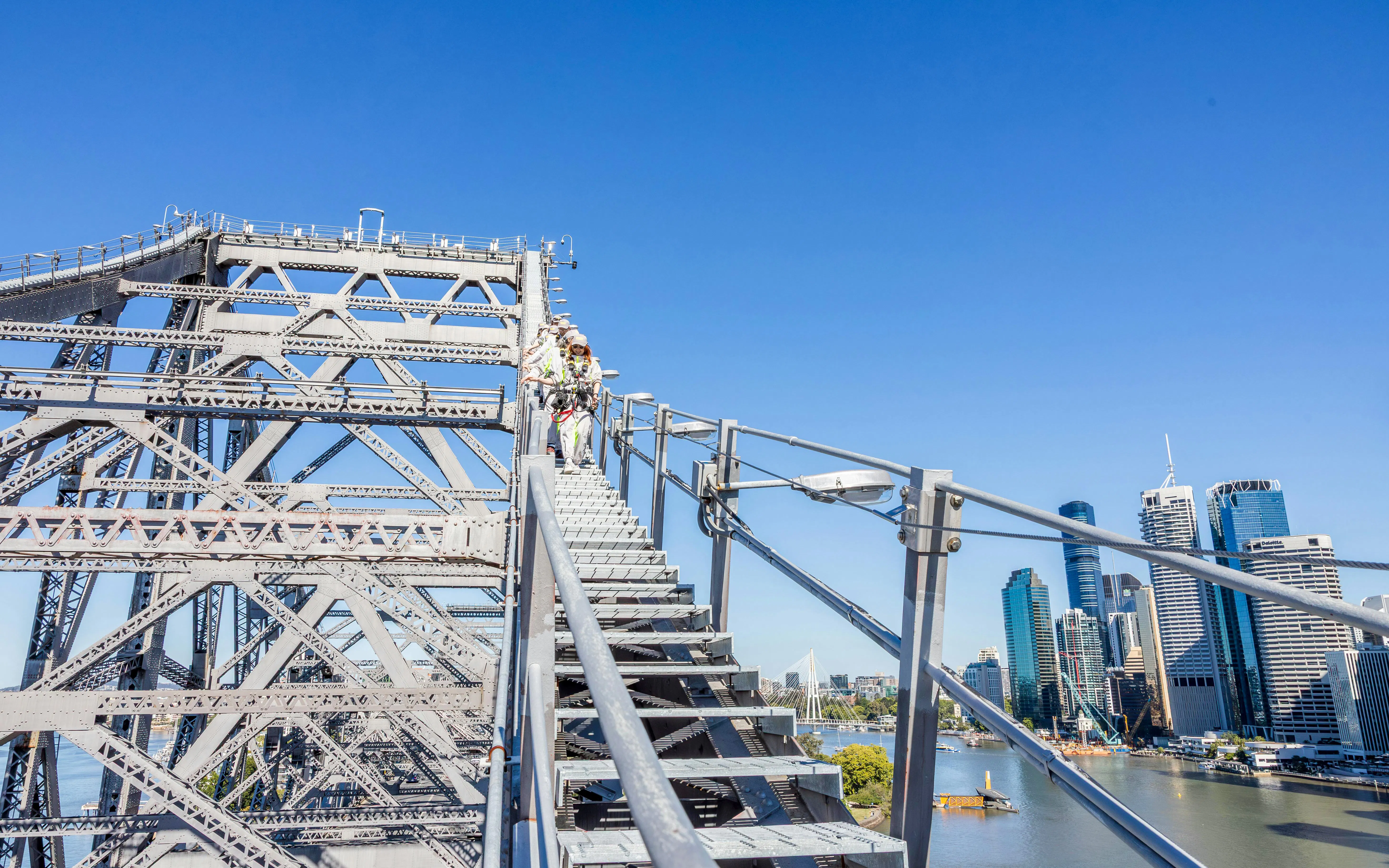 Climbers ascending Story Bridge with Brisbane skyline in the background.