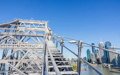 Climbers ascending Story Bridge with Brisbane skyline in the background.