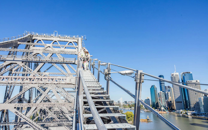 Climbers ascending Story Bridge with Brisbane skyline in the background.