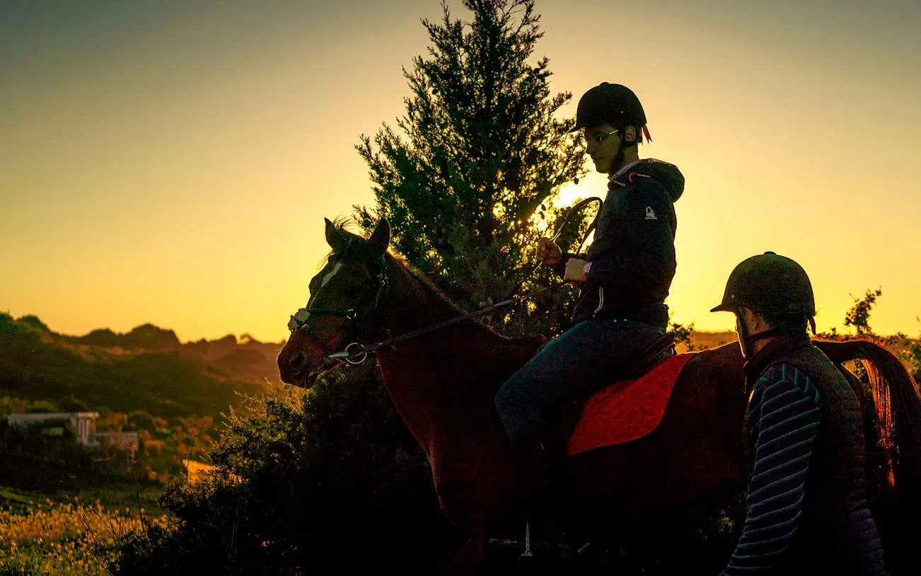 Horseback riders on a trail at sunset in Mnar, Tangier.